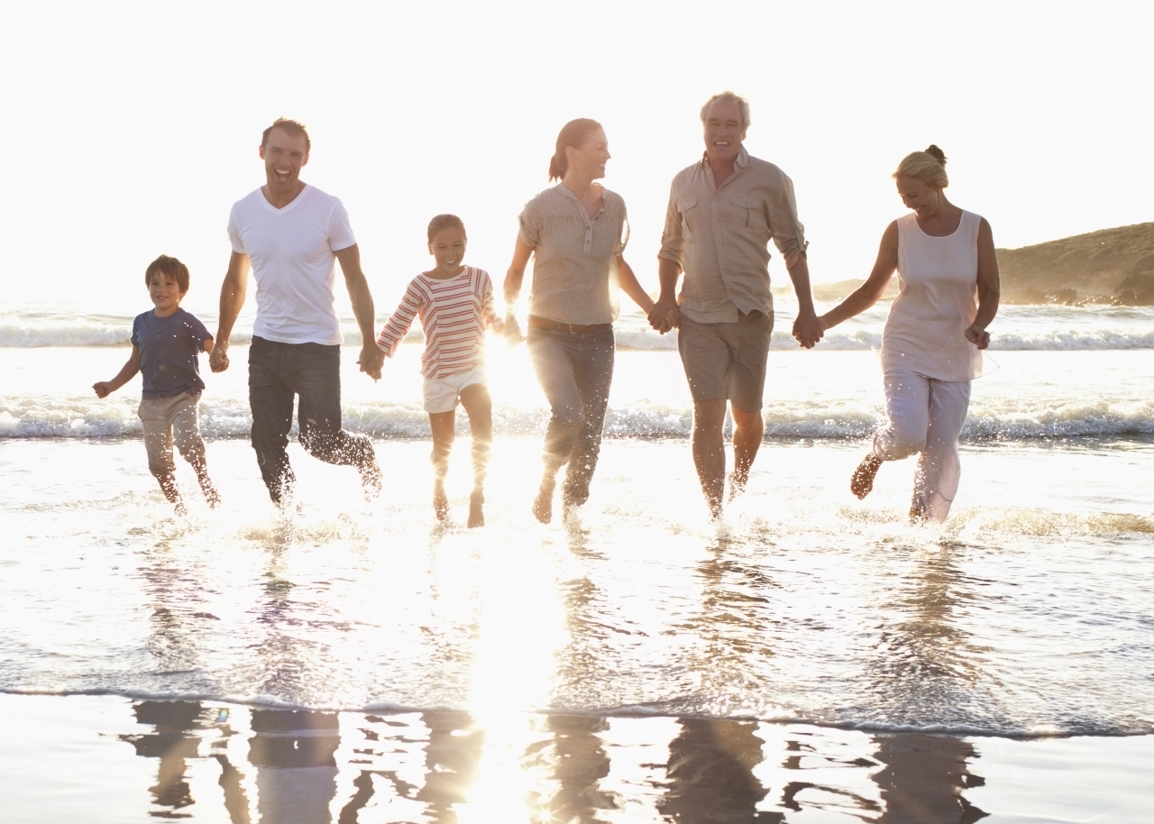 Family holding hands in water at beach wading in the water